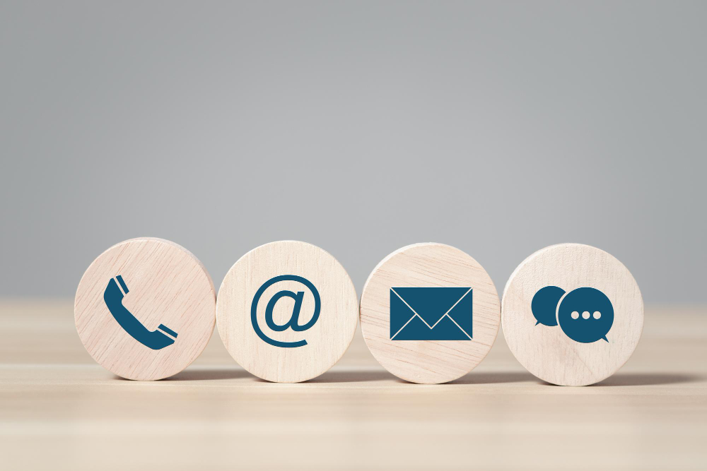 Holzscheiben mit Symbolen für Telefon, E-Mail, Brief und Chat